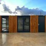 Container Ufficio 7 x 3 m — Listoni in Legno Naturale Verticali e Vetrate Panoramiche Antracite - immagine 1
