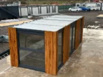 Container Ufficio 7 x 3 m — Listoni in Legno Naturale Verticali e Vetrate Panoramiche Antracite - immagine 9