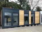 Container Ufficio 8 x 3 m — Facciata Grigia con Tre Fasce di Legno Orizzontale e Vetrate - immagine 1