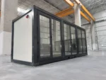 Container Ufficio Modello Falcón 2,4 x 6,0 m — Facciata con Vetrate a Tutta Altezza in Alluminio Verde/Teal e Pannelli Bianchi - immagine 1