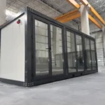 Container Ufficio Modello Falcón 2,4 x 6,0 m — Facciata con Vetrate a Tutta Altezza in Alluminio Verde/Teal e Pannelli Bianchi - immagine 1