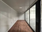 Container Ufficio Modello Falcón 2,4 x 6,0 m — Facciata con Vetrate a Tutta Altezza in Alluminio Verde/Teal e Pannelli Bianchi - immagine 8